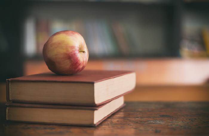 Apple on a desk on top of two books